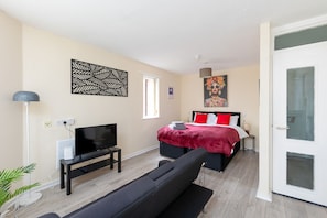 A modern bedroom with a bed, a TV, and a sofa. - 1BR Flat w/ King sized beds | Near Station (Stockton-on-Tees)