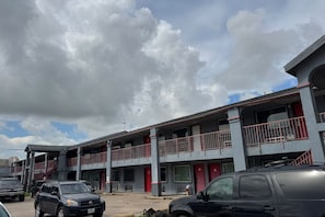 Um motel com vários andares, varandas, estacionamento e céu claro.