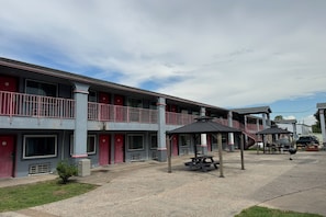 Ein Motel mit zweistöckiger Bauweise, Sitzbereich im Freien und einem überdachten Picknicktisch.