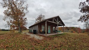 Un rustico chalet con un portico, immerso in un prato cosparso di foglie.