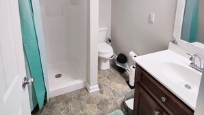 Un bagno con doccia, wc, lavandino e specchio.