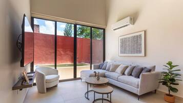 Una sala moderna con sofá, sillón, mesa de centro y televisor.