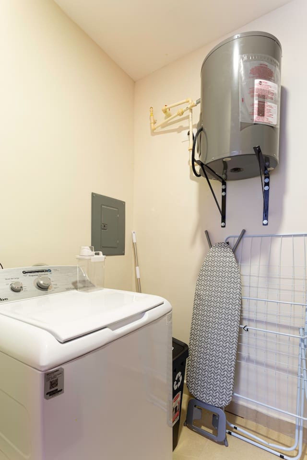 A laundry area with a washing machine, a drying rack, and a water heater.