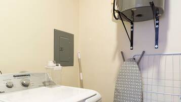 A laundry area with a washing machine, a drying rack, and a water heater.