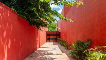 A narrow pathway flanked by red walls with a gate at the end.