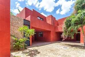 Ein modernes Gebäude mit roter Fassade, einer Steinwand und einem Kopfsteinpflasterhof.