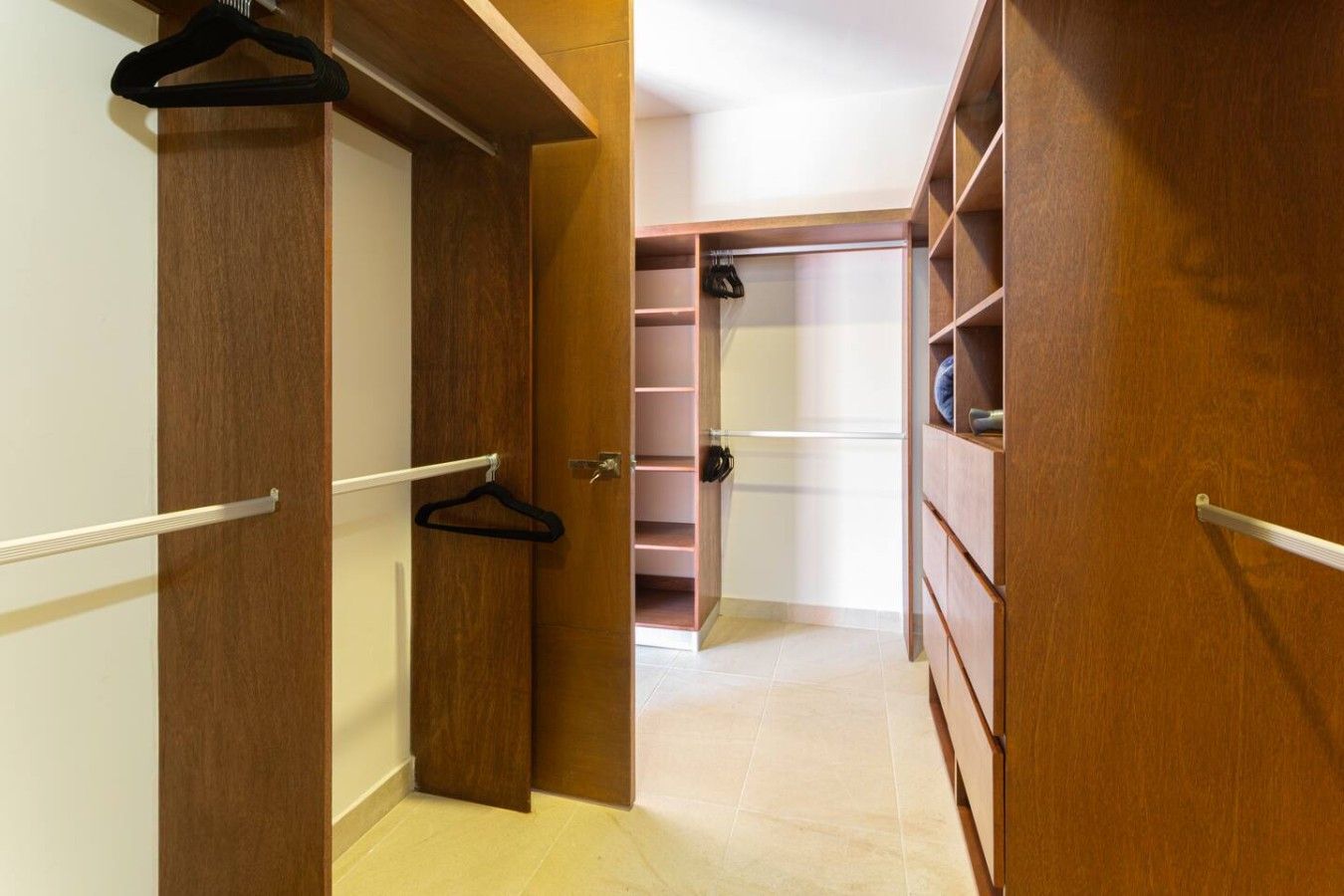 Un vestidor con puertas de madera, estantes múltiples y espacio para colgar ropa.
