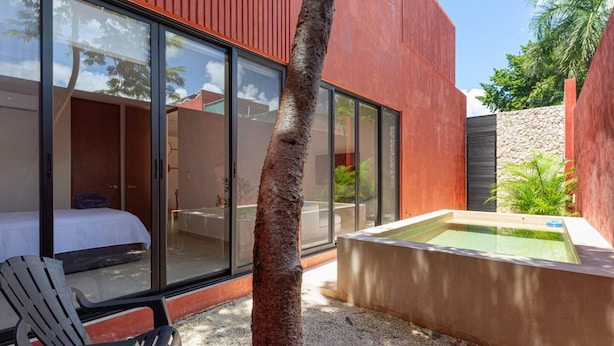 Zona exterior moderna amb un llit, una cadira i una petita piscina.