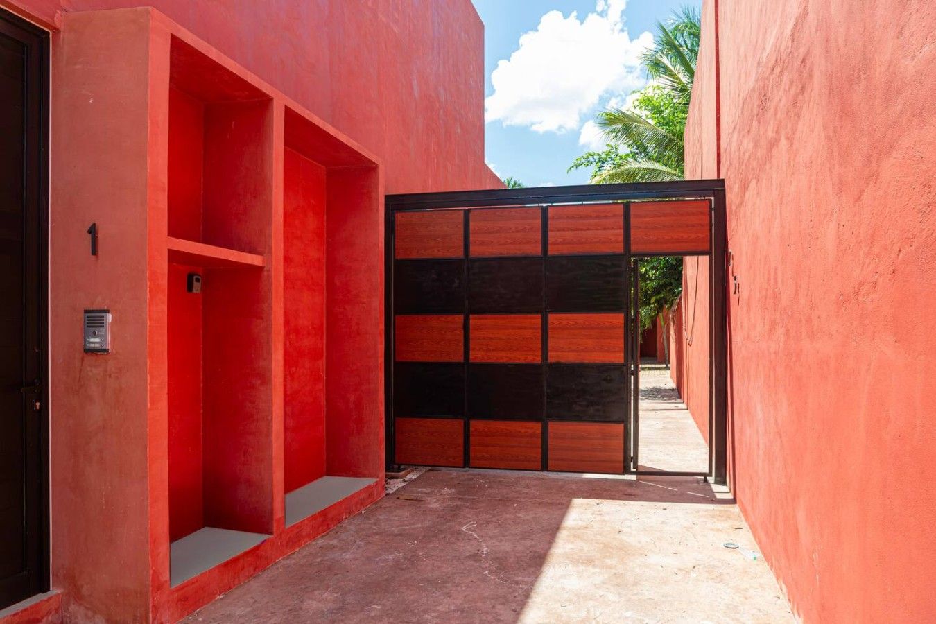 Un estrecho callejón con una pared roja y una puerta de madera.