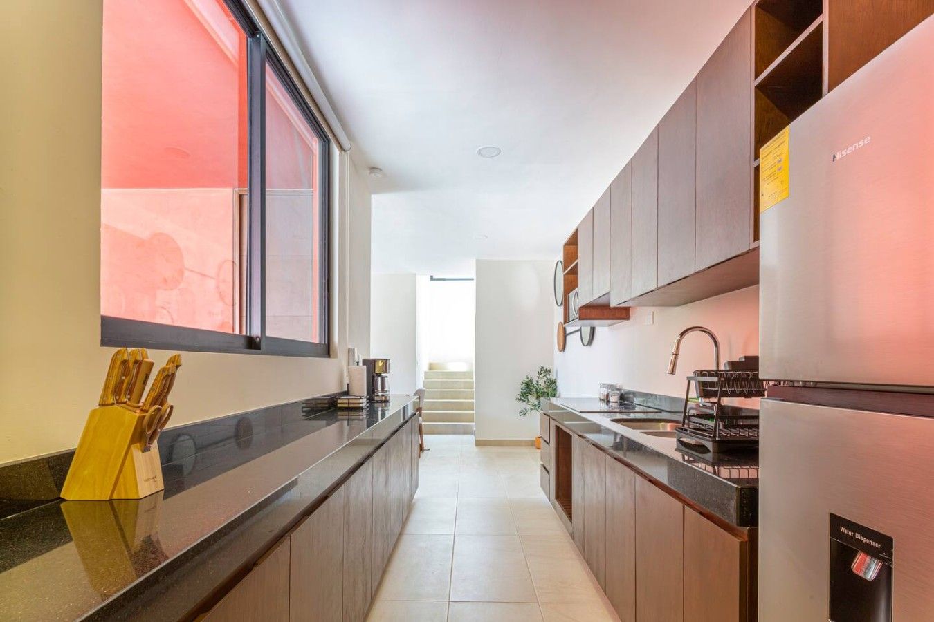 Una cocina moderna con encimera negra, armarios de madera y refrigerador de acero inoxidable.