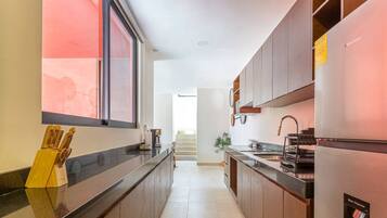 Una cocina moderna con encimera negra, armarios de madera y refrigerador de acero inoxidable.