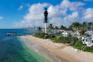A coastal scene with a lighthouse, beach, and residential buildings. - Waterfront Oasis • Heated Pool & Spa • Near Beach (Oakland Park)