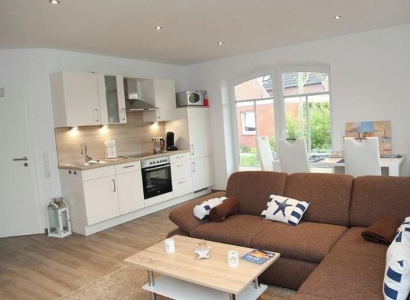 A modern kitchen with white cabinets, a built-in oven, and a microwave. - Holiday Apartment in Greetsiel With Terrace (Krummhoern)