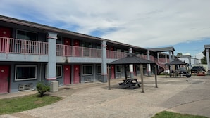 Ein Motel mit zweistöckiger Bauweise, Sitzbereich im Freien und einem überdachten Picknicktisch.