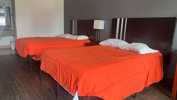 Ein Hotelzimmer mit zwei Betten, jeweils mit roter Bettdecke und weißen Kissen.