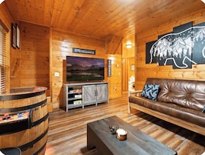 Ein Holzinnenraum mit einem Ledersofa, einem Fernseher und einer Bar.