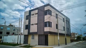 Un edificio moderno de dos pisos con techo plano, ventanas grandes y una puerta de garaje amarilla.