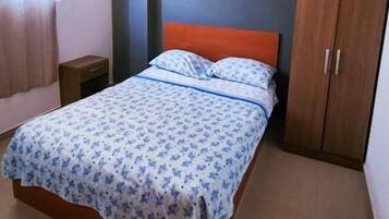 A bedroom with a bed, a wardrobe, and a nightstand.