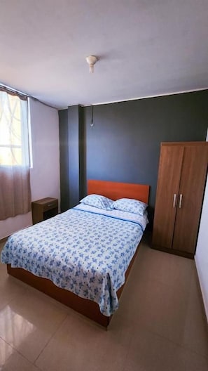 A bedroom with a bed, a wardrobe, and a nightstand. - VALLE DEL SOL HOTEL (Ica)