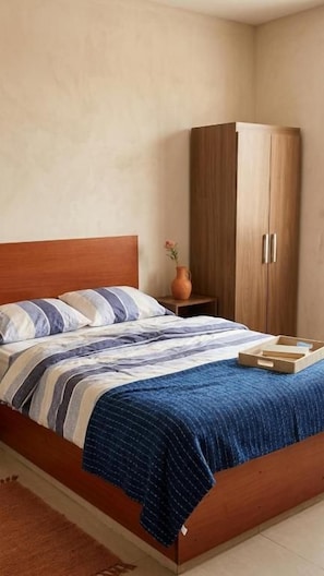 A bedroom with a wooden bed, a nightstand, a wardrobe, and a vase with flowers. - VALLE DEL SOL HOTEL (Ica)