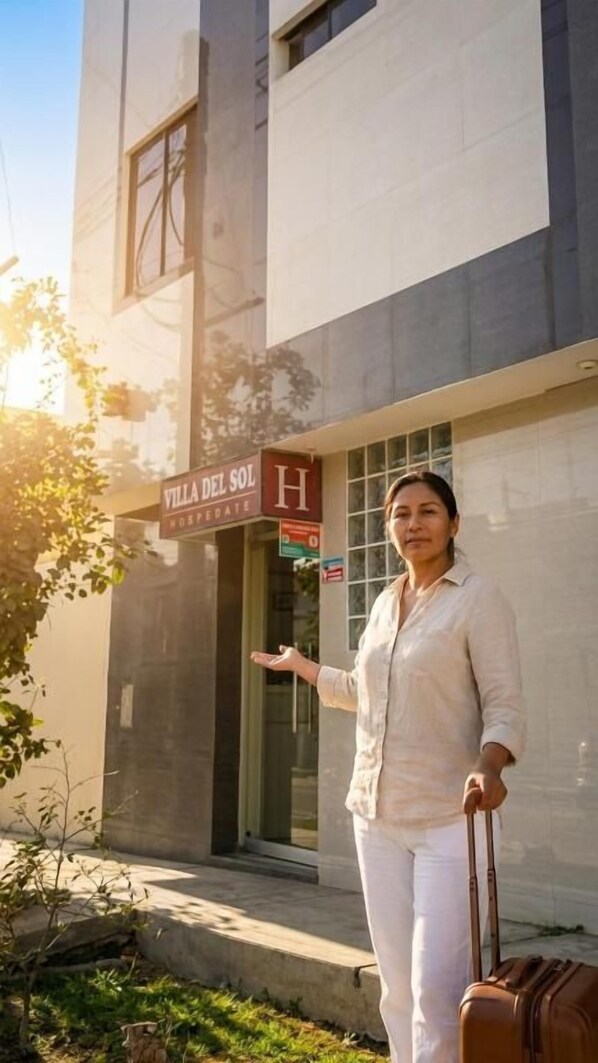 Una persona de pie frente a un edificio con un letrero que dice 'Villa del Sol Hotel'.