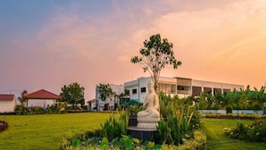 Una estatua en un jardín ajardinado con un edificio moderno al fondo.