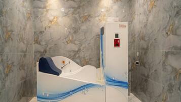 A modern spa room with a massage chair and a control panel.