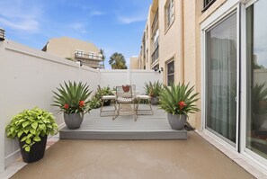 Pátio com mesa e cadeiras, cercado por plantas em vasos.
