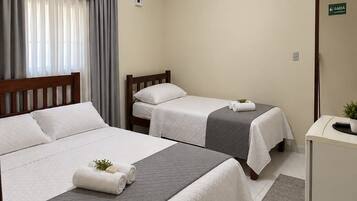 Ein Hotelzimmer mit zwei Betten, einem Schreibtisch, einem Spiegel und einem Vorhangfenster.