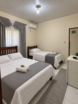 Una habitación de hotel con dos camas, un escritorio, un espejo y una ventana con cortinas.