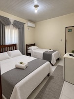 Una habitación de hotel con dos camas, un escritorio, un espejo y una ventana con cortinas.
