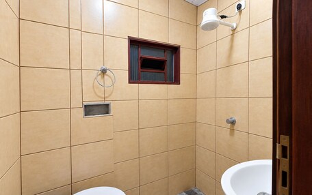 A bathroom with two sinks, a toilet, a shower head, and a window.