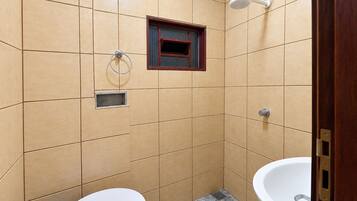 Ein Badezimmer mit zwei Waschbecken, einer Toilette, einer Duschbrause und einem Fenster.