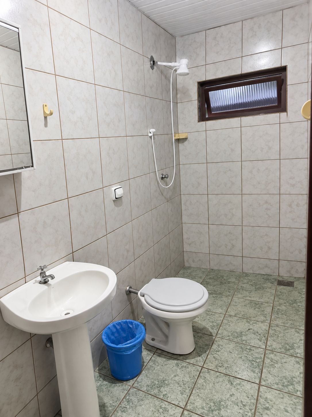 Ein Badezimmer mit Waschbecken, Toilette, Dusche und einem kleinen Fenster.