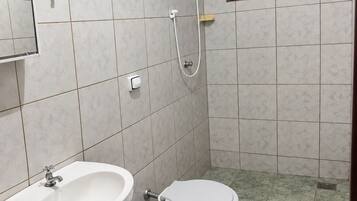 Ein Badezimmer mit Waschbecken, Toilette, Dusche und einem kleinen Fenster.