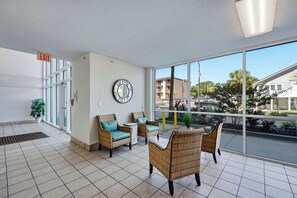 Eine Lobby mit Korbmöbeln, einer Wanduhr und einem großen Fenster mit Blick nach draußen.
