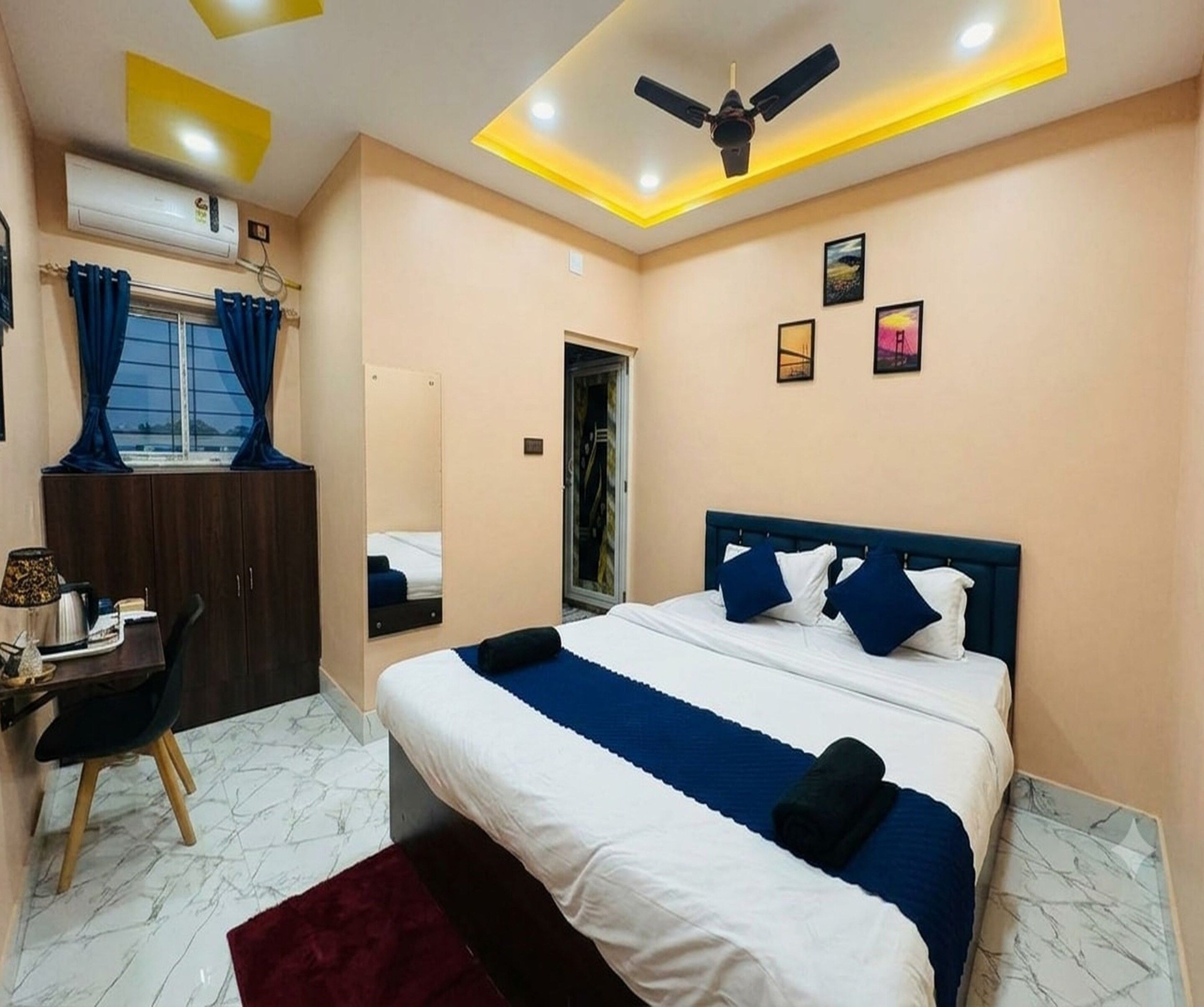 Habitación de hotel con cama, escritorio, silla y ventilador de techo.