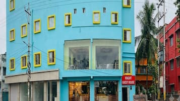 Un edificio de varios pisos con fachada azul y marcos de ventana amarillos, que cuenta con un restaurante en la planta baja con mesas visibles y un letrero que dice 'KNIGHT GUEST HOUSE'.