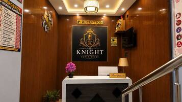A reception desk with a 'RECEPTION' sign above it, a 'NO SMOKING' sign to the left, and a 'THE KNIGHT GUEST HOUSE' sign above the desk.
