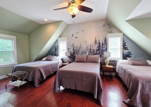 Ein Schlafzimmer mit zwei Betten, einem Deckenventilator und einem Wandbild von einem Wald.