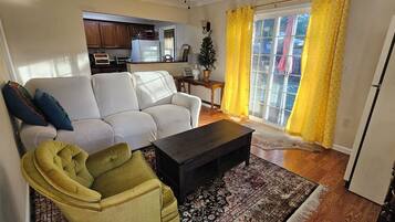 Una sala de estar con sofá, sillón, mesa de centro y alfombra estampada.
