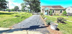A residential driveway leading to a house with a front yard, a mailbox, and a street sign.