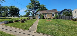 A residential house with a front yard, a pathway leading to the front door, and a small garden area.