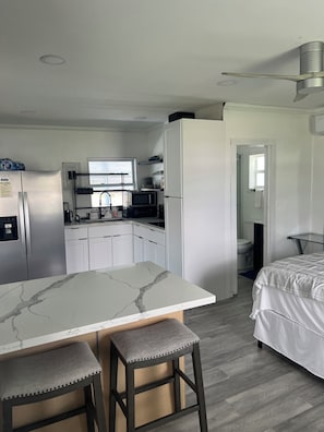 A compact kitchen with a marble countertop, a refrigerator, a microwave, and a sink. - Waterfront home with a screened in porch (Okeechobee)