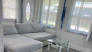 Un soggiorno moderno con un divano componibile, un tavolino in vetro e una porta con un elegante vetro decorativo.