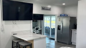 Una cucina moderna con frigorifero integrato, ventola a soffitto e angolo bar con sgabelli.