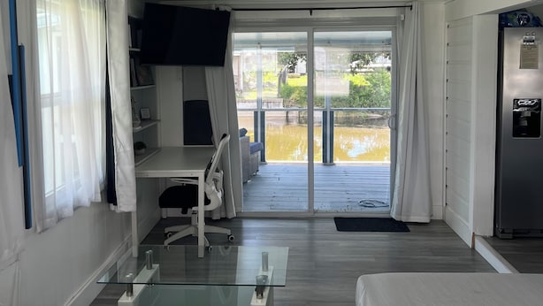 Una camera d'albergo con un letto, una scrivania, una sedia, una TV e una porta-finestra che dà su uno spazio esterno.