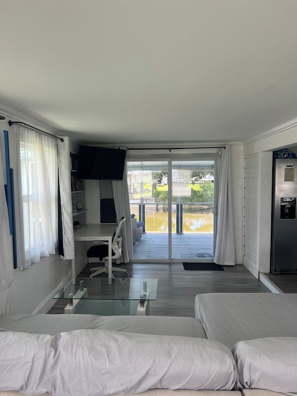 A hotel room with a bed, a desk, a chair, a TV, and a sliding glass door leading to an outdoor area. - Waterfront home with a screened in porch (Okeechobee)