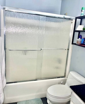 A bathroom with a shower enclosure, a toilet, and a shelf with toiletries. -  Centrally located room in Glendale (Glendale)