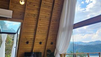 A dining area with a wooden ceiling, a table with chairs, and a view of the outdoors.